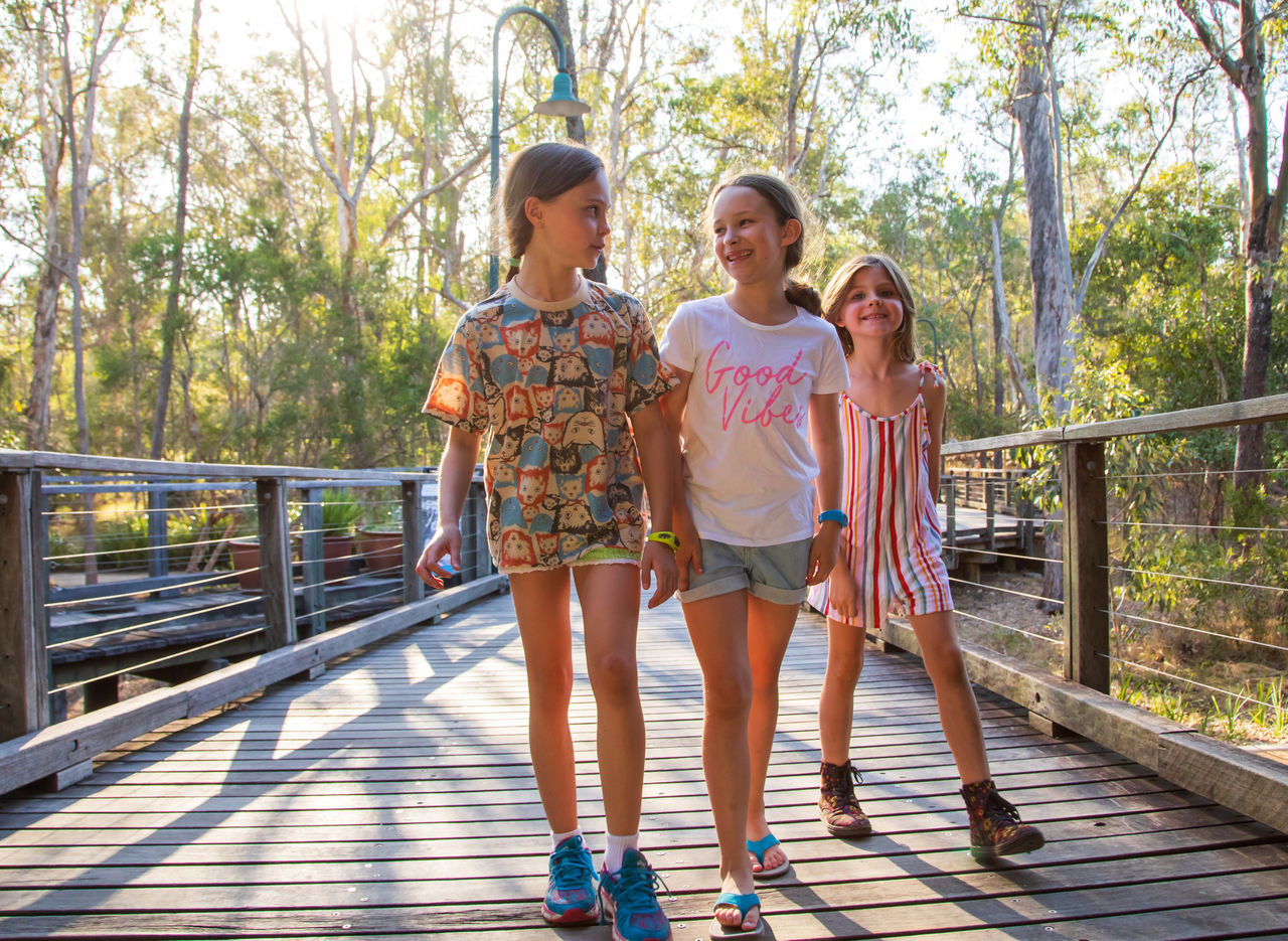 Woman riding an e-scooter along the Brisbane River at New Farm. Bright blue sky as background.