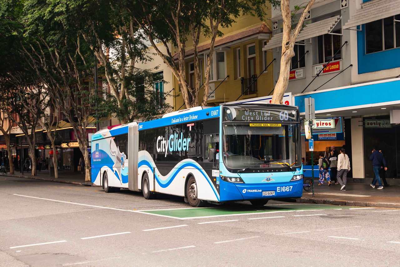 Blue-toned CityGlider bus driving along Melbourne Street, South Brisbane.