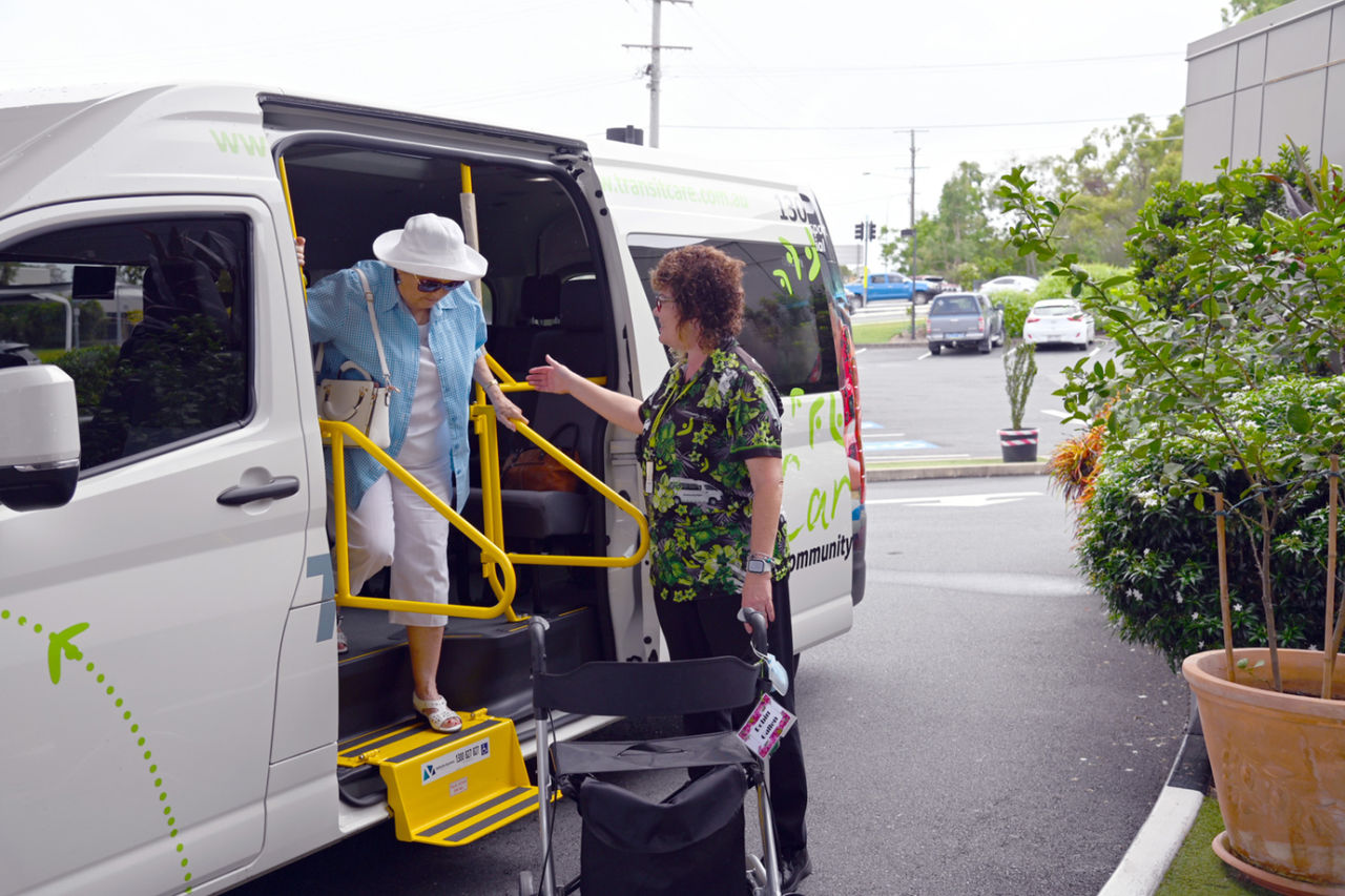 A male cab driver assisting a female passenger into a Council Cab.