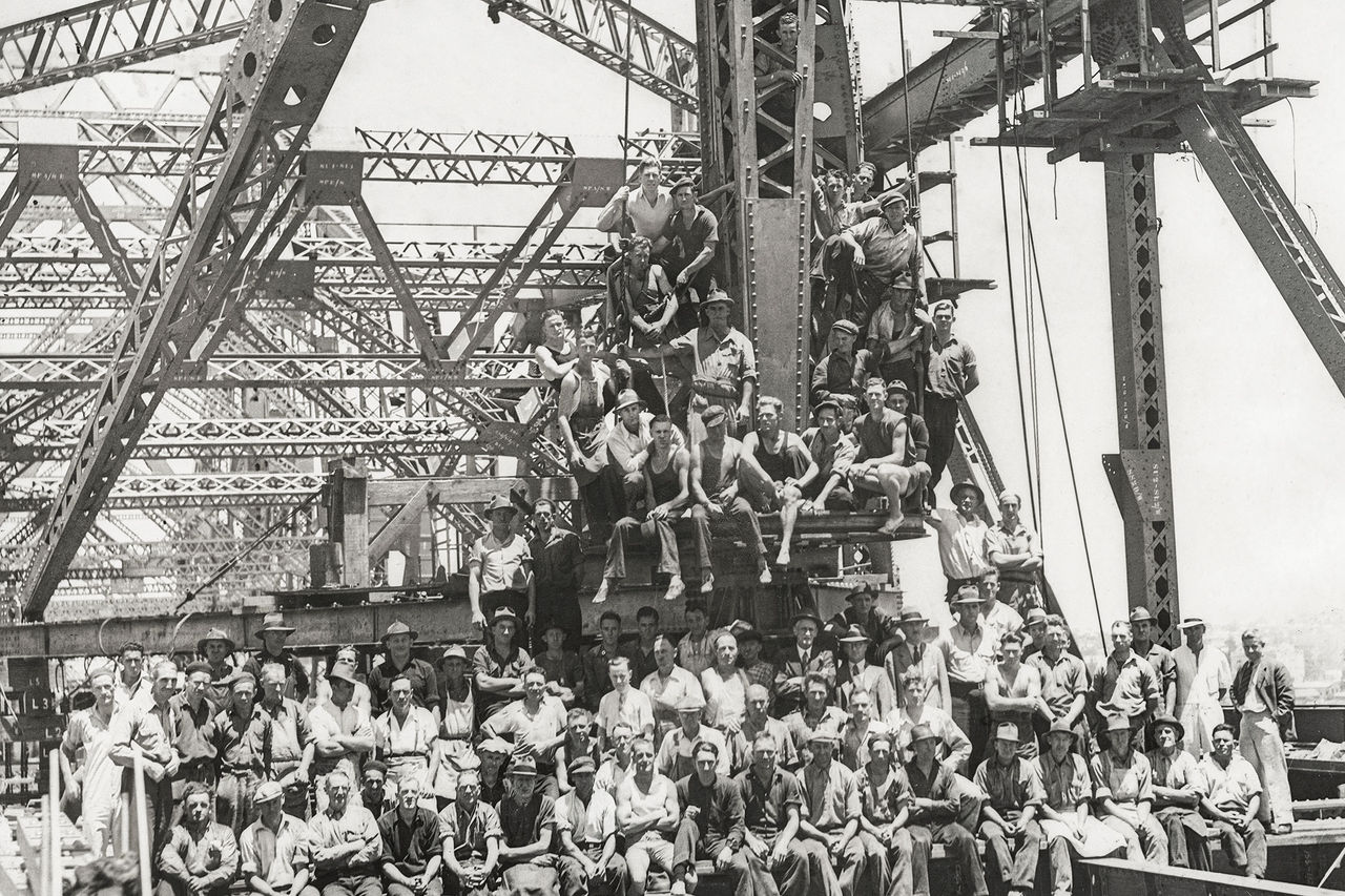 Historical, black and white image of group of construction workers on the Story Bridge.