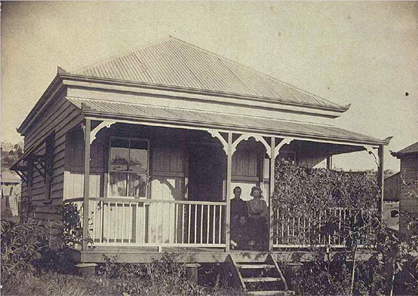 Historical image of the residents of Carew Cottage sitting on its verandah.