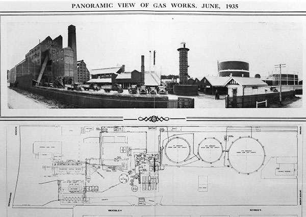 This is a black and white panoramic photo of the South Brisbane Gas Works in June 1935. It shows a complex of various industrial buildings and a central space where 7 vehicles are parked. A cylindrical gas stripping tower decorated with square panels can be seen to the left.  This is a black and white image of a schematic drawing of the South Brisbane Gas Works in 1935. It shows a floor plan view of the complex and its buildings, including the demountable gas stripping tower.