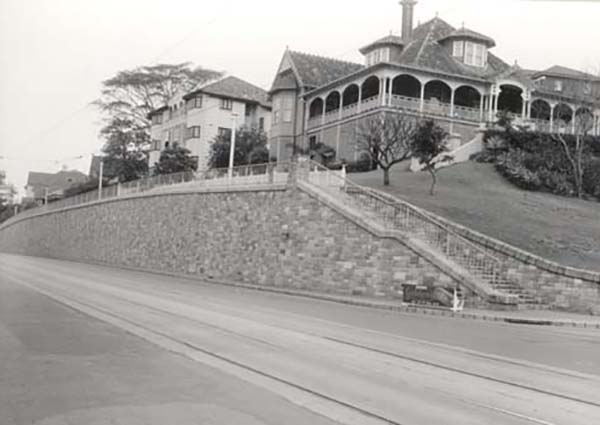 This is a black and white photograph of Hamilton Road No.2 that also shows the Hamilton villas 'Blair Lodge' and 'Greystaines' in 1961. Hamilton Road is in the foreground before the large stone retaining wall. On the right are stairs leading to a pedestrian footpath along the top of the retaining wall. Other houses above the retaining wall can be seen in the background.