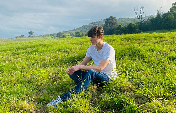 Image of artist Blakey J sitting amongst green grass