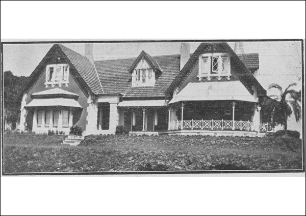 A newspaper clipping with a picture of Shafston, a single storey masonry residence with steeply pitched tiled roof and gables featuring bay window on one side of a stone portico and an open verandah on the other.