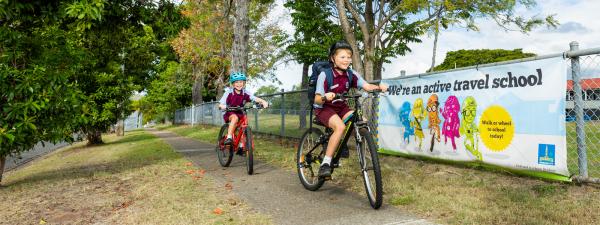 Two school children in uniform riding bikes to school